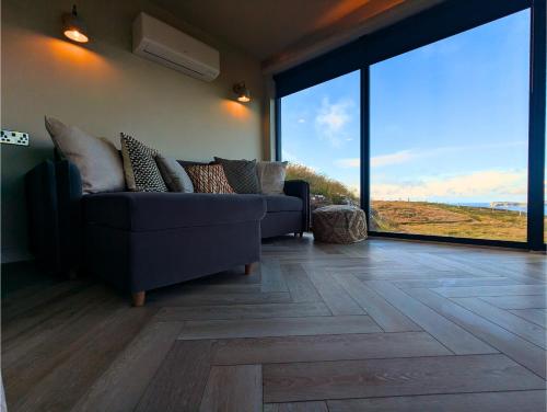 a living room with a blue couch and large windows at Carrick-a-Rede Luxury Retreat Ballintoy Causeway Coast in Ballintoy