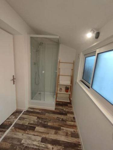 La salle de bains est pourvue d'une douche en verre et d'une fenêtre. dans l'établissement Studio à 5 min de Narbonne, à Coursan