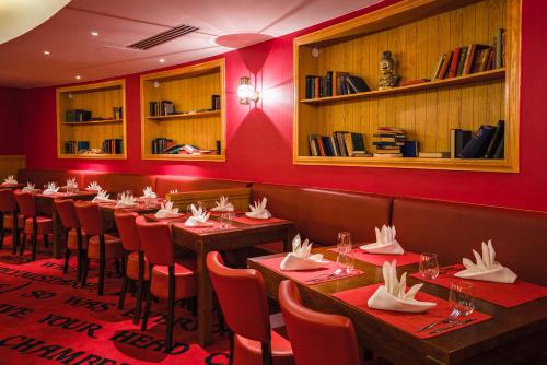a restaurant with wooden tables and red walls at Explorers Hotel Marne-la-Vallée in Magny-le-Hongre
