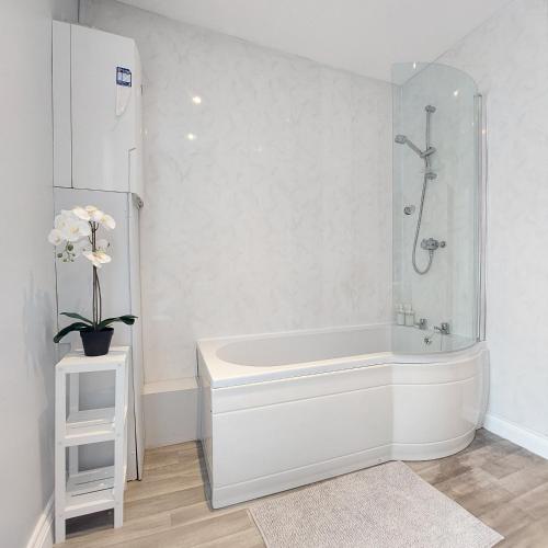 a white bathroom with a tub and a shower at Amber Lodge- No party Room in Belfast