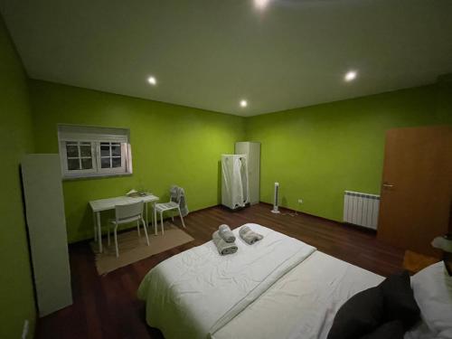 a green room with a bed and a table at Casa rua do Capitão in Póvoa de Lanhoso
