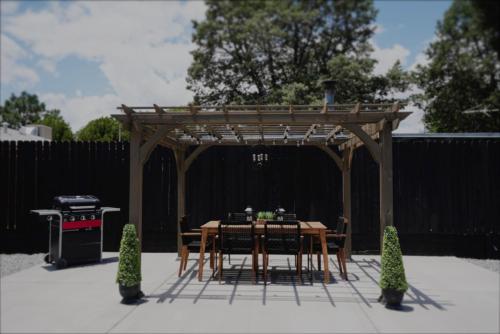 a wooden pergola with a table and chairs and a grill at Centrally Located! Remodeled! Huge Backyard! The White House in Albuquerque