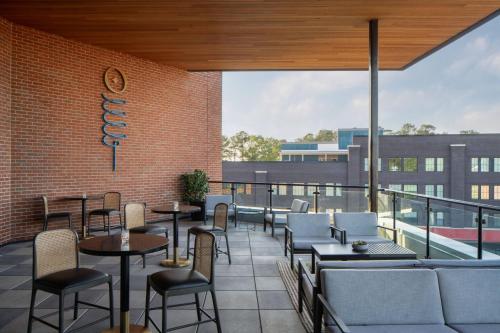 a restaurant with tables and chairs on a balcony at Trilith Guesthouse, Fayetteville, GA, a Tribute Portfolio Hotel in Fayetteville