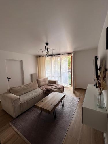 a living room with a couch and a table at Très beau T3 Neuf a Franconville in Franconville