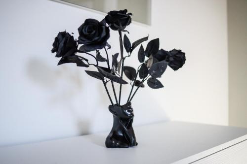 a black vase with black roses in it at LUSSO e DESIGN, APPARTAMENTO 6 MINUTI AEROPORTO ORIO AL SERIO in Seriate