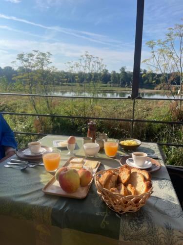 une table avec de la nourriture et une corbeille de pain et de jus d'orange dans l'établissement Chambres privées au dessus du restaurant Nuances, à La Chapelle-sur-Loire