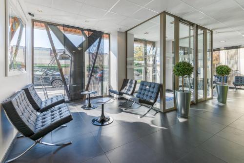 a lobby with two chairs and glass windows at Lagrange Aparthotel Lyon Lumière in Lyon