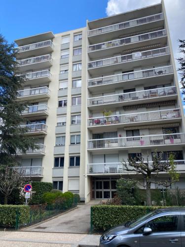 un immeuble d'appartements avec une voiture garée devant lui dans l'établissement Cosy flat 2 chambres, à Saint-Étienne