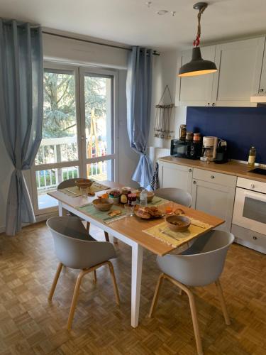 cocina con mesa de madera y sillas en Cosy flat 2 chambres, en Saint-Étienne