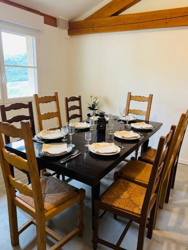 - une salle à manger avec une table, des chaises, des assiettes et des verres dans l'établissement Les terres du Sotison, à Vaux-en-Beaujolais