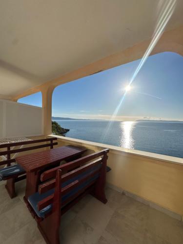 a table and bench in a room with a view of the ocean at Apartments Alać in Drasnice