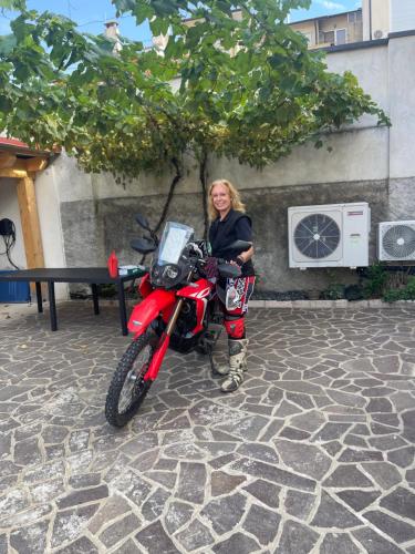 a woman is standing next to a red motorcycle at casa carmelo in Schio