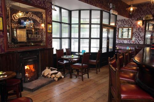 a bar with a fireplace and a table and chairs at Waterfoot Hotel in Derry Londonderry