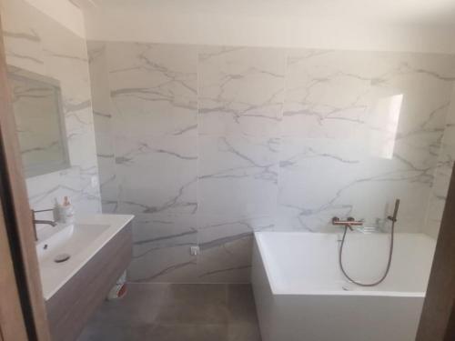 La salle de bains blanche est pourvue d'une baignoire, d'un lavabo et d'une baignoire. dans l'établissement Villa t4, à Lucciana