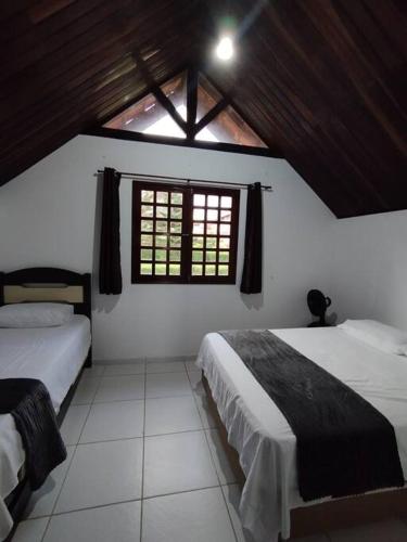 a bedroom with two beds and a window at Chalé Paisagem Serrana in Bananeiras