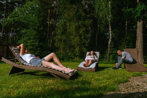 a group of people laying on wicker chairs in the grass at Chata w Leśnych Pieleszach - sauna & balia z jacuzzi na wyłączność in Łukawica