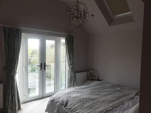 a bedroom with a bed and a large window at Spacious 4 bed house 10 min from Silverstone in Helmdon