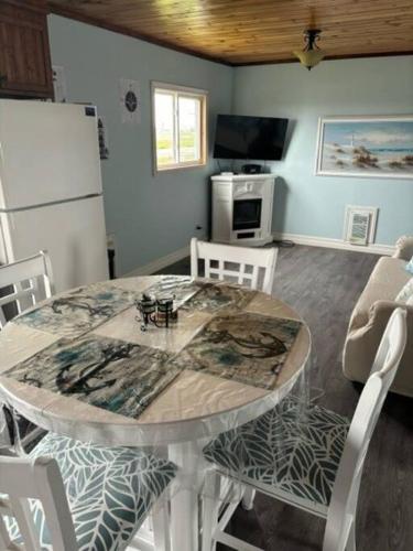 a dining room with a table and a refrigerator at Sea Captains Cabin in Lamaline