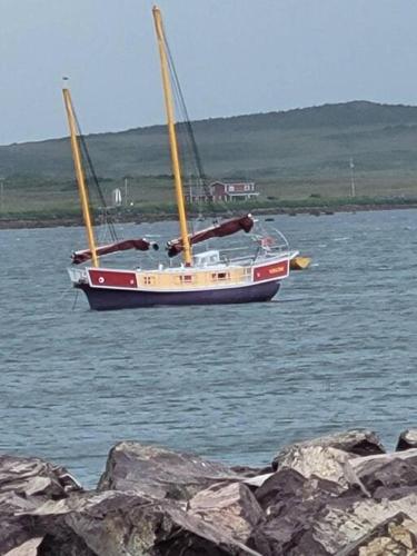 a sail boat in the water near some rocks at Sea Captains Cabin in Lamaline