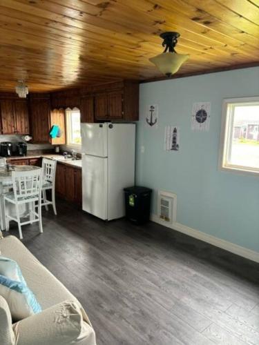 a living room with a white refrigerator and a kitchen at Sea Captains Cabin in Lamaline