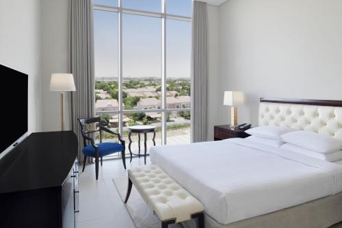 a bedroom with a white bed and a large window at Delta Hotels by Marriott Dubai Investment Park in Dubai