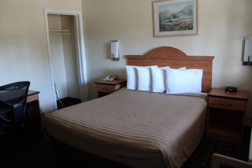 a hotel room with a bed with white pillows at Riverside Inn & Suites Santa Cruz in Santa Cruz