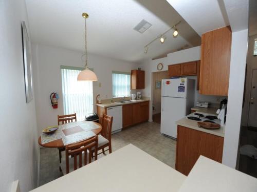 a kitchen with a table and a white refrigerator at Three-Bedroom House in Clear Creek in Orlando