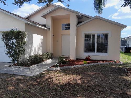 a white house with a tree in front of it at Three-Bedroom House in Clear Creek in Orlando