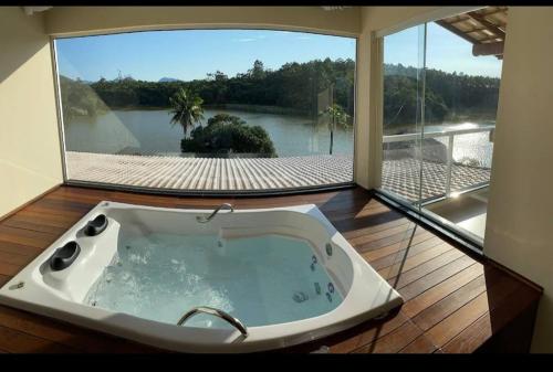 a bath tub in a room with a large window at Pousada Peninsula Santa Rita in Guarapari