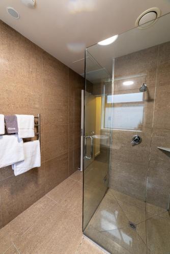 a bathroom with a glass shower with towels at 315 Euro Motel and Serviced Apartments in Dunedin