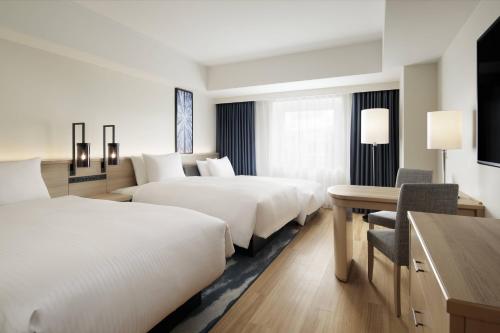 a hotel room with two beds and a desk at Fairfield by Marriott Sapporo in Sapporo