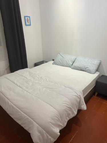 - un lit avec des draps blancs et un oreiller bleu dans l'établissement Comme a la maison, à Béziers