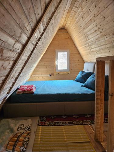 a bed in a tiny house with a wooden ceiling at Cabană la LERI in Icloda