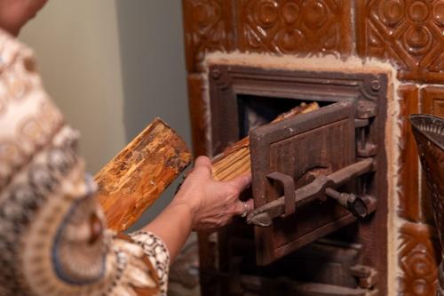 a person is putting something into an oven at Chata w Leśnych Pieleszach - sauna & balia z jacuzzi na wyłączność in Łukawica