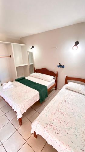 a bedroom with two beds and a mirror at Pousada Do Vozinho in Touros