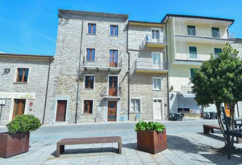 a large stone building with benches in front of it at La plaza in Ollolai