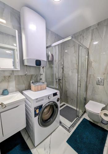 y baño con lavadora y ducha. en Dea apartment, en Dobra Voda