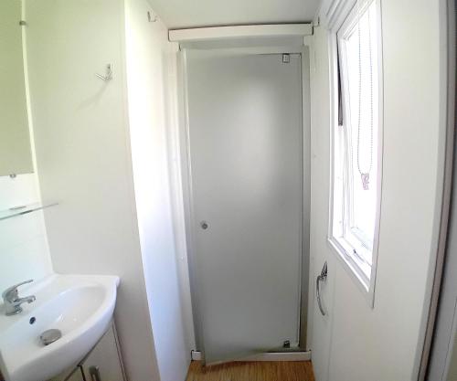 une salle de bain blanche avec un lavabo et une fenêtre dans l'établissement Mobil home 2 chambres Saint-Jean-de-Monts, à Saint-Jean-de-Monts