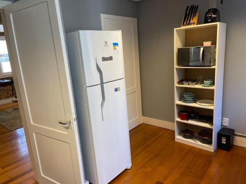 a white refrigerator in a kitchen next to a pantry at Prédio Histórico na Rio Branco in Caxias do Sul