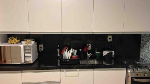 a kitchen counter with a sink and a microwave at Prédio Histórico na Rio Branco in Caxias do Sul
