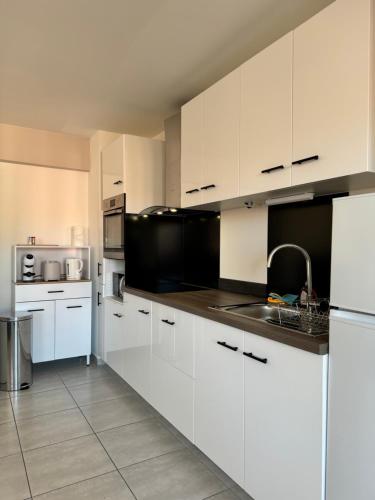 une cuisine avec des armoires blanches et des appareils noirs dans l'établissement T3 Vue sur le port, à Ajaccio