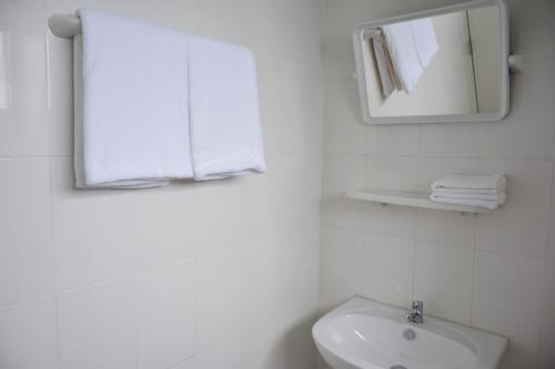 a white bathroom with a sink and a mirror at Annex Lumpini Bangkok in Bangkok