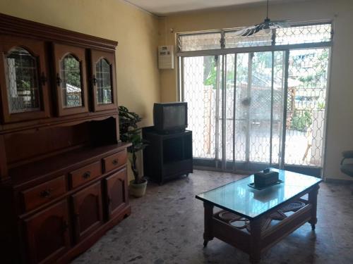 a living room with a tv and a coffee table at Escapade Creole Maison Rustique avec accès à la plage à la Baie du Moule in Le Moule