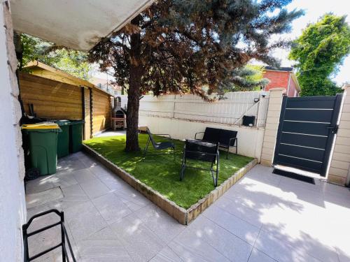 a patio with chairs and a tree and a fence at Superbe studio avec entrée et jardin privés à moins de 15 minutes de Paris in Bagneux
