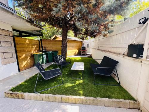 trois chaises et une table sur une parcelle d'herbe dans l'établissement Superbe studio avec entrée et jardin privés à moins de 15 minutes de Paris, à Bagneux