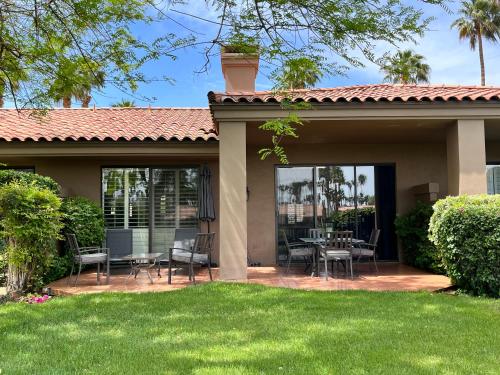 a patio with chairs and tables in a yard at Relax in Palm Valley Comfort in Palm Desert