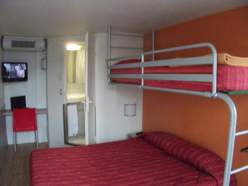 - une chambre avec des lits superposés et un couvre-lit rouge dans l'établissement Premiere Classe Bayonne, à Bayonne