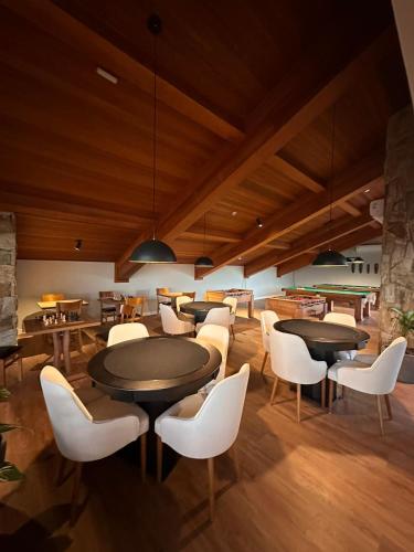 a dining room with tables and white chairs at Wanderlust Experience Hotel in Campos do Jordão