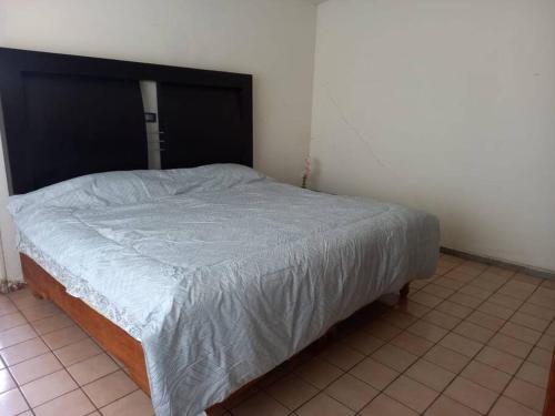 a bed in a bedroom with a black headboard at Residencia Villegas in Delicias