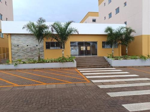 a yellow building with palm trees in a parking lot at Apartamento completo em Santarém in Santarém